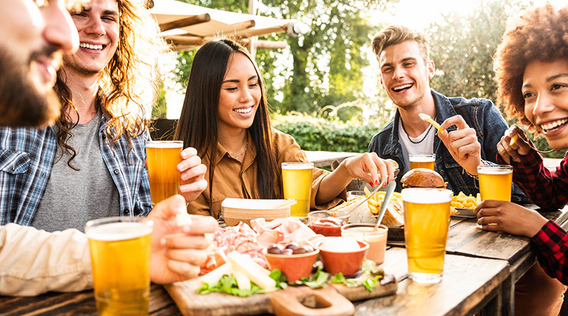Young adults enjoying food and beer outside in the sun