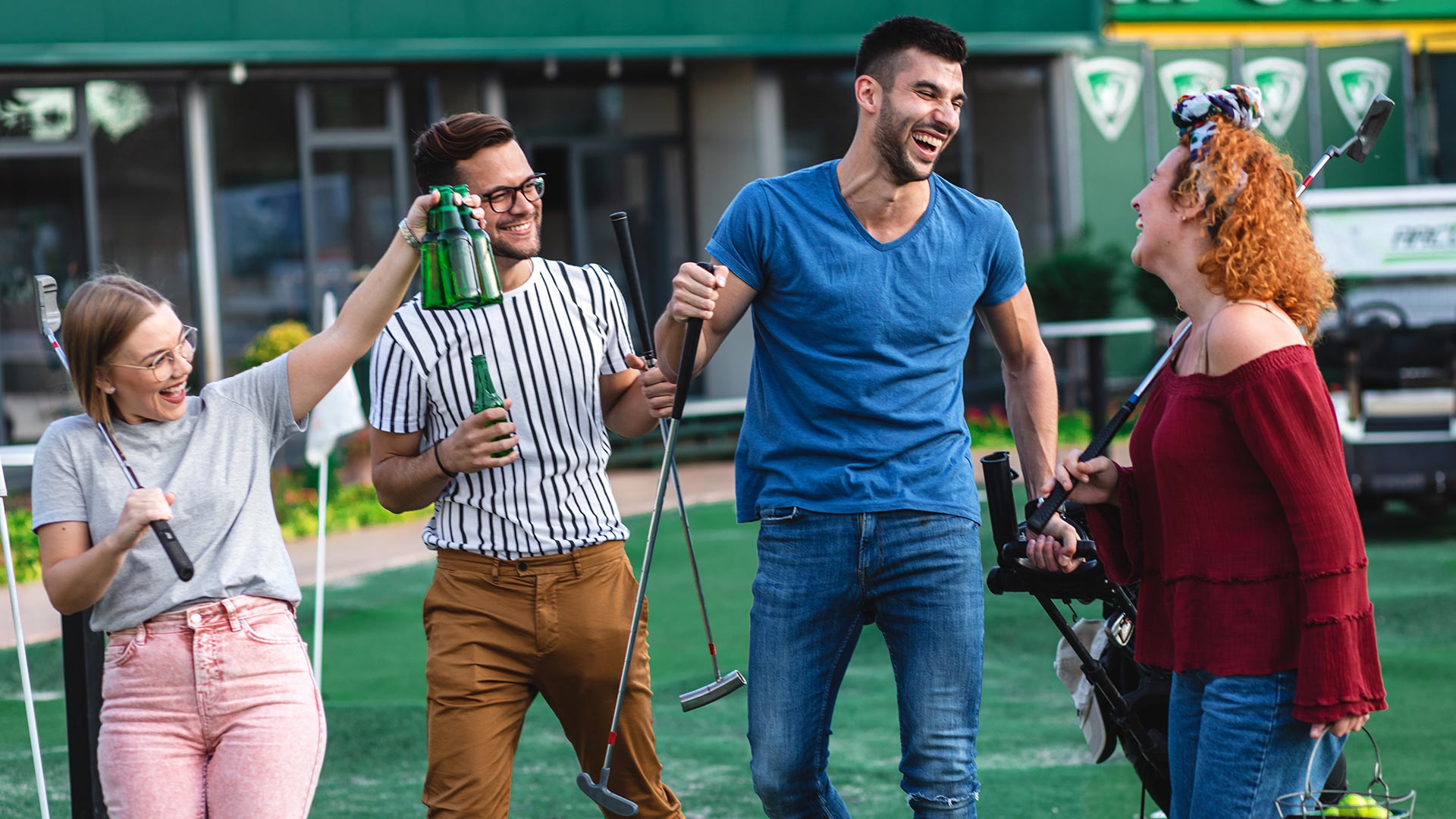 Two young men and 2 young women enjoying adventure golf and drinking beer